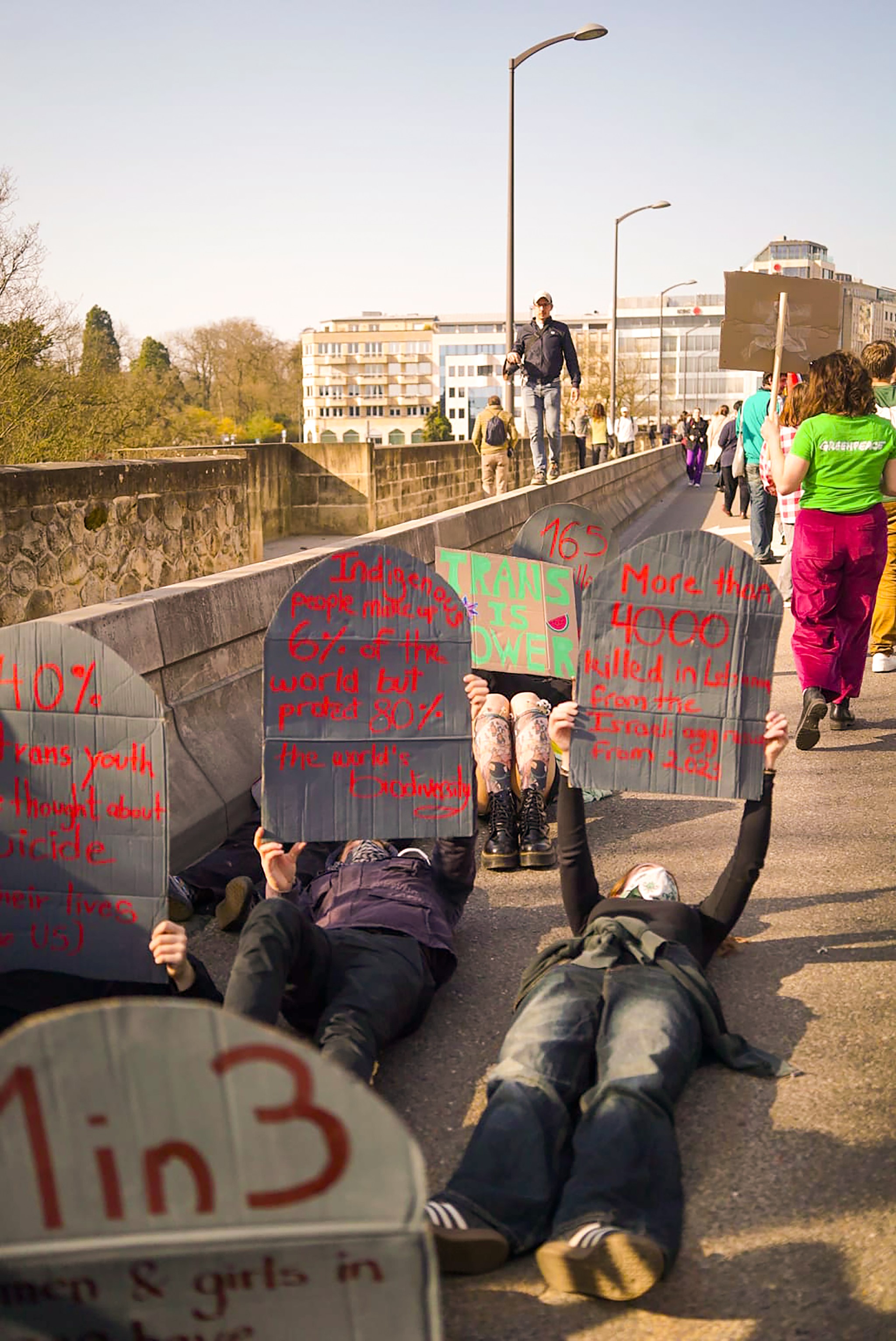 Picture of people lying on the ground holding up cardboard gravestones with statistics on violence against marginalised people.